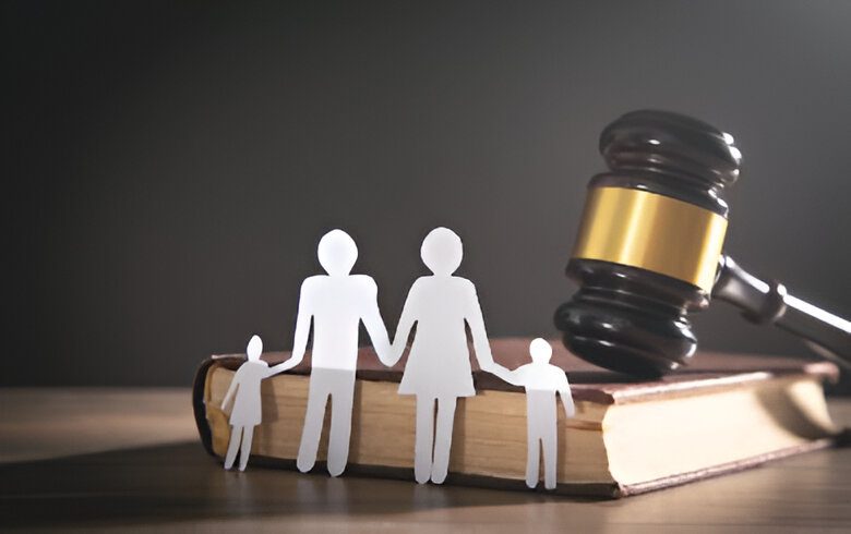 Paper cutouts of a family on a book with a gavel nearby, symbolizing family law or legal matters.